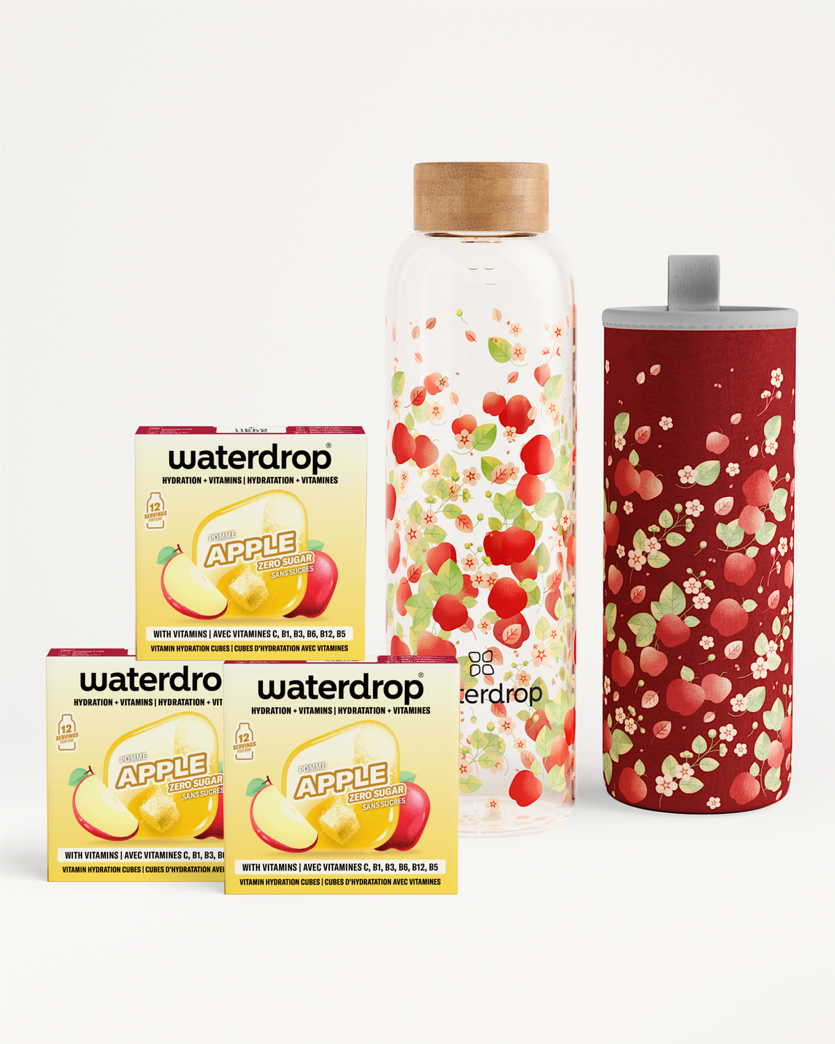 Assorted drink flavor enhancers with apple-flavored boxes, a fruit-filled glass bottle, and a red speckled tumbler.