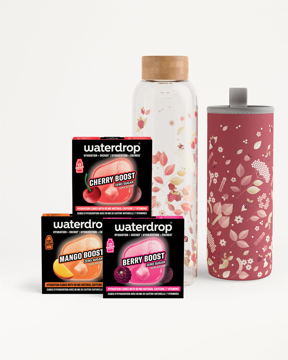 Assortment of three flavor boost sachets beside a clear glass bottle with a wooden cap and a tall pink floral-patterned tumbler.