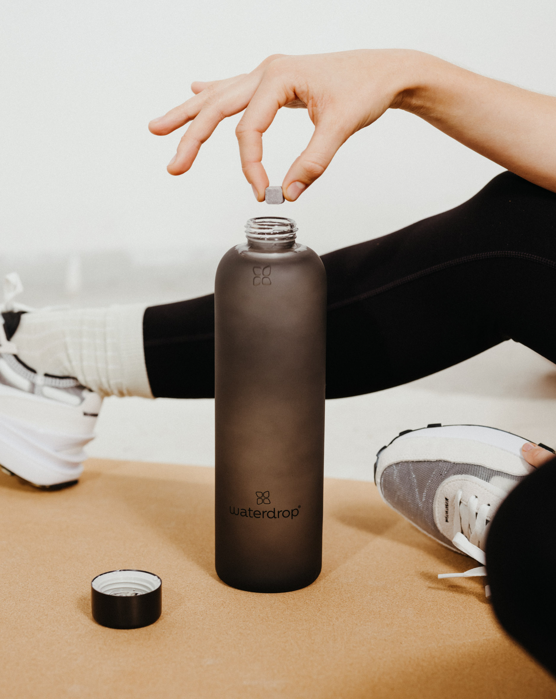 Frosted Glass jar shown close-up, with a person's hand inserting a pill, highlighting its durable borosilicate design for lasting use at home or on the go.