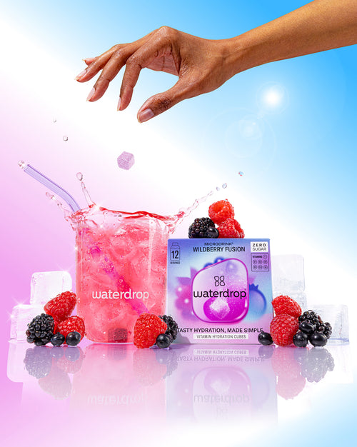 WILDBERRY FUSION vitamin-hydration cube dropping into a pink berry drink with ice, beside a Wildberry Fusion box, fresh berries, and ice cubes.