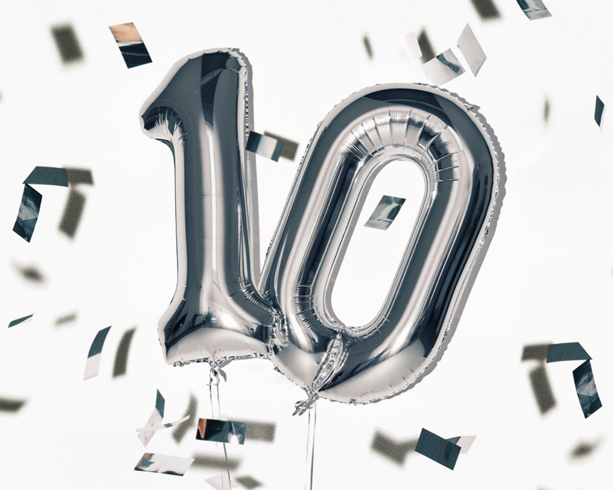 Foil silver number balloons forming '10' with scattered confetti for celebration.