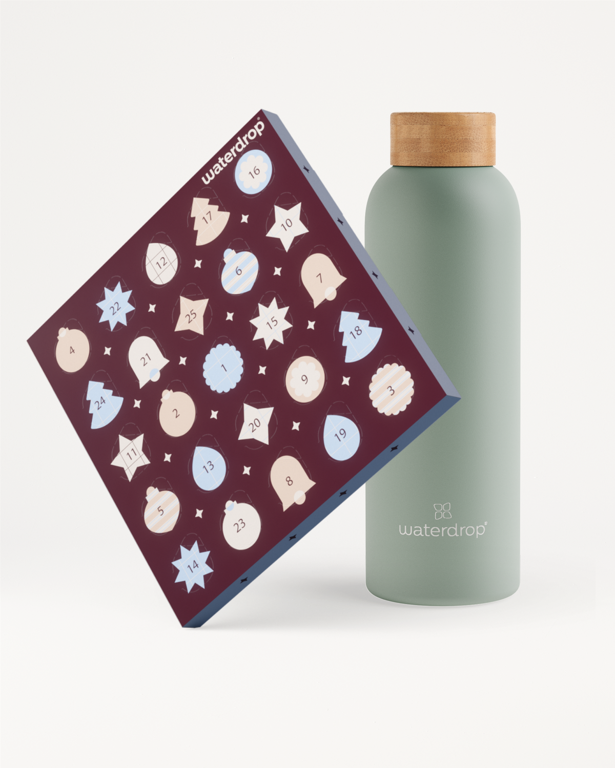 Tilted dark purple box with many light-colored circular icons beside a pale green bottle with a wooden cap.