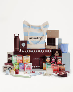 Assorted boxed products and containers arranged around a striped tote bag to form a gift set.