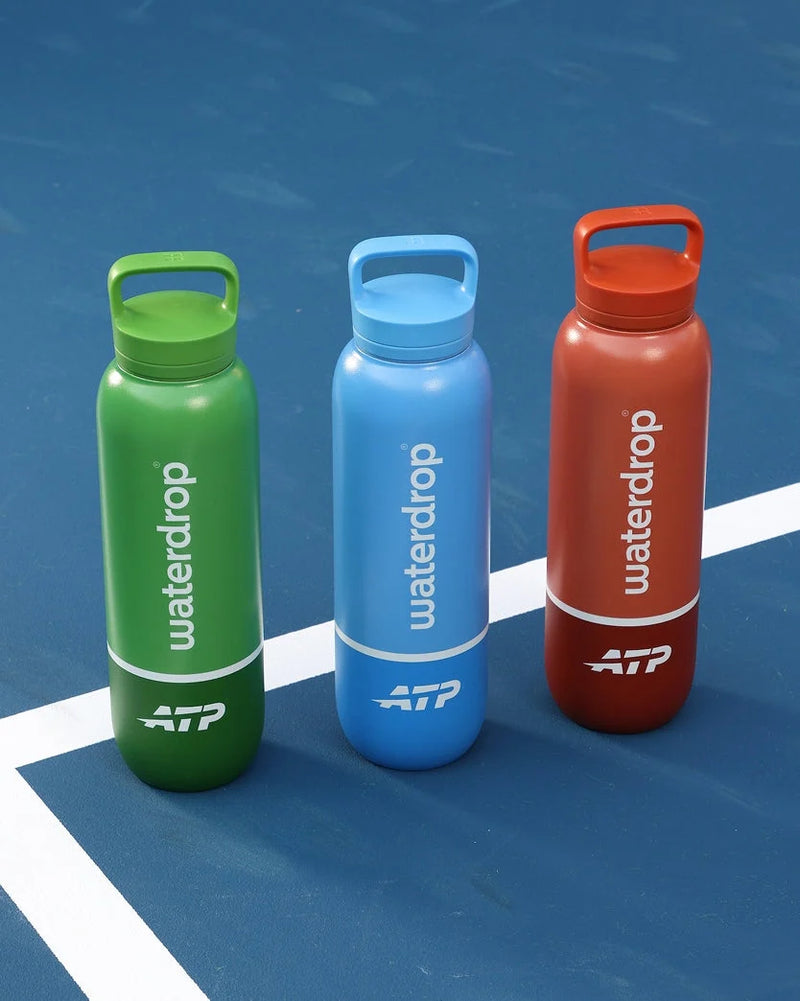 Three colored sport water bottles on a blue tennis court.