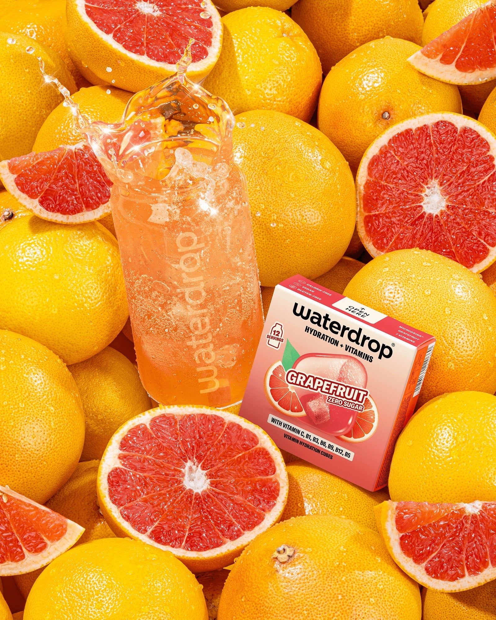 Assortment of grapefruits with a pink grapefruit-flavored beverage bottle and a small box among the fruit.