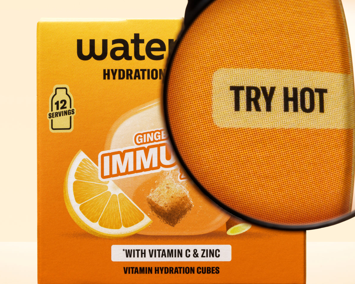 Orange box with a lemon graphic and a magnifying glass overlay, highlighting vitamin hydration cubes.