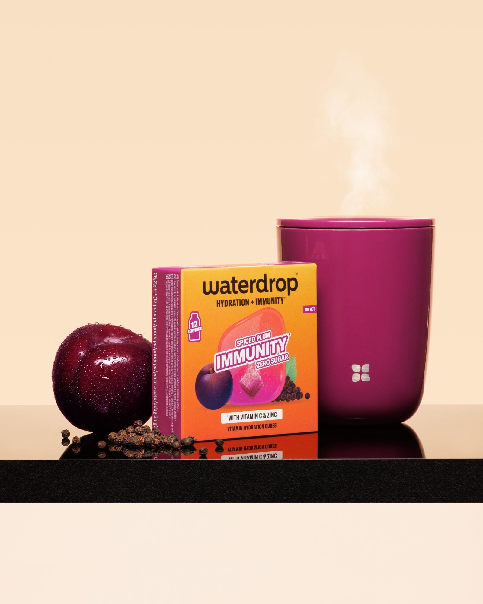 Waterdrop immunity boost box with a plum and a steaming pink mug on a black surface.
