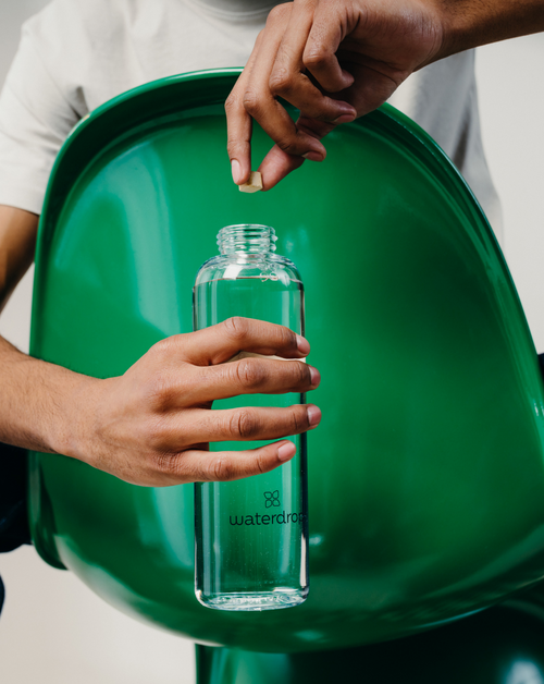 Hand holding a Starter Set Microdrink Glass bottle ideal for sampling six Microdrink flavors. Includes a high-quality Borosilicate Glass Bottle available in 600ml or 1L.